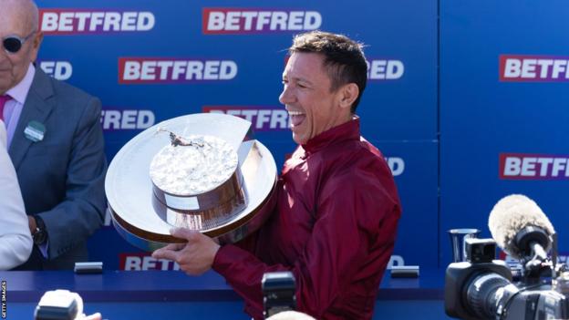 Frankie Dettori holds up the trophy in celebration after winning the Oaks at Epsom