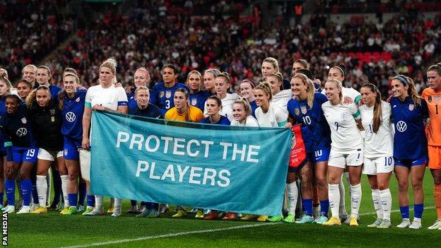 England and the United States hold up a banner saying protect the players