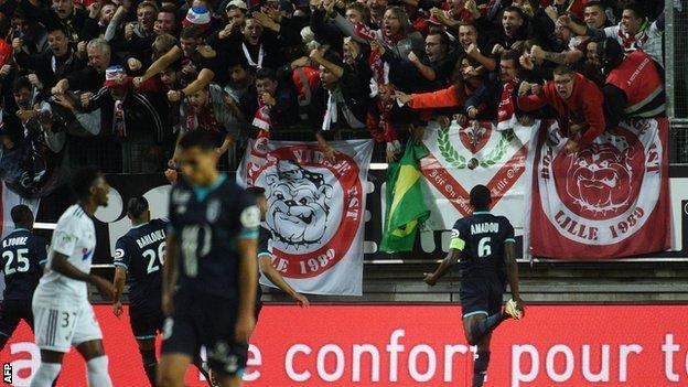 Lille supporters celebrate before the barrier collapses