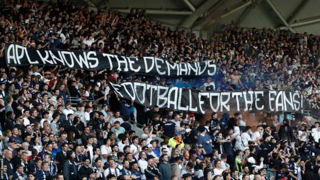 Melbourne Victory fans hold a banner protesting against the APL