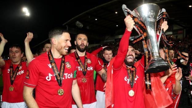 Elliot Lee raises the National League winner's trophy with Wrexham team mates