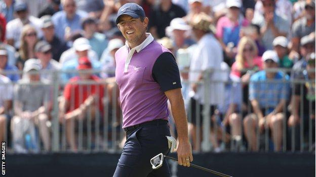 Rory McIlroy smiles with fans behind him