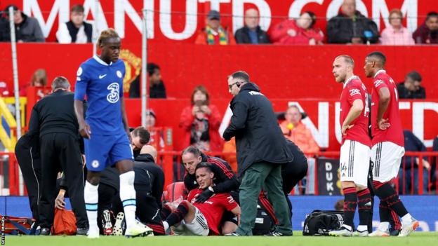 A visibly upset Antony receives treatment on the pitch while some of his Manchester United team-mates look on