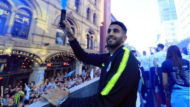 Riyad Mahrez of Manchester City holds a flare on board a bus during the Manchester City parade