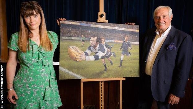 Sir Gareth Edwards and artist Elaine Sian Blake with a painting of Edwards scoring 'the greatest attempt' against New Zealand in 1973