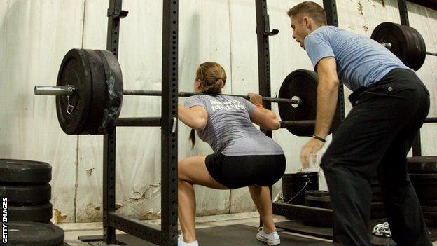 Woman being coached weightlifting