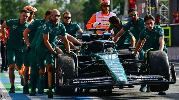 Aston Martin mechanics wheel Lance Stroll's car back to the pit lane after it stopped during Italian Grand Prix second practice