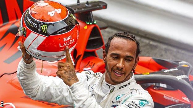 Lewis Hamilton holds up his helmet in tribute to Niki Lauda