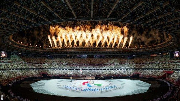 Havai fişekler, aşağıda sergilenen Paralimpik logosu olan Agitos ile Tokyo Ulusal Stadyumu'nun üzerindeki gökyüzünü aydınlatıyor