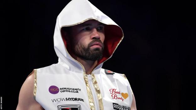 John Ryder in a white, hooded ring outfit before a fight