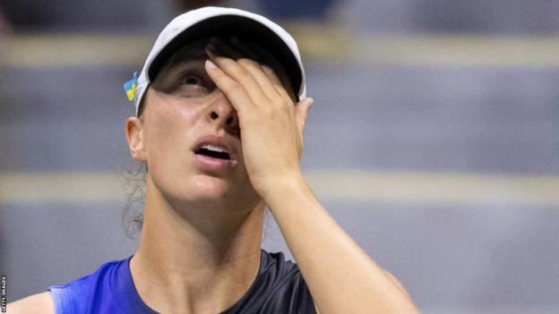 Iga Swiatek covers her look   during a US Open decision   by Jelena Ostapenko