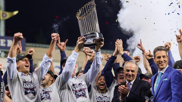 The Atlanta Braves lift the World Series trophy, watched by MLB commissioner Rob Manfred (second right, in dark suit)