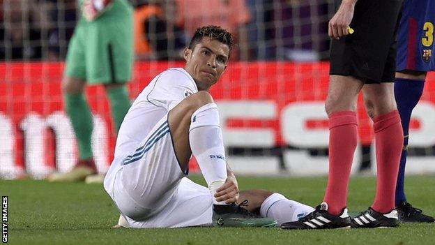 Real Madrid's Cristiano Ronaldo holds his ankle after spraining it against Barcelona