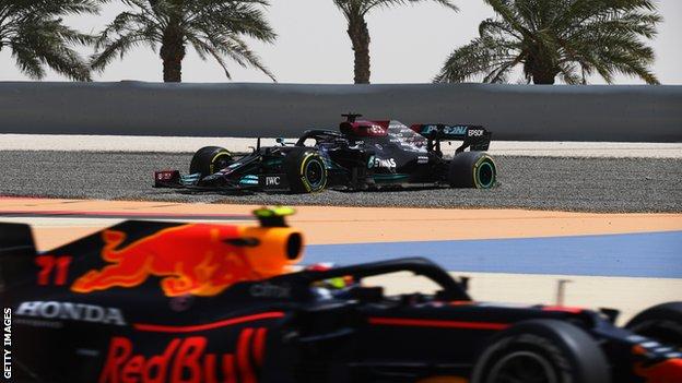 Lewis Hamilton in the gravel during testing as Red Bull's Sergio Perez races past