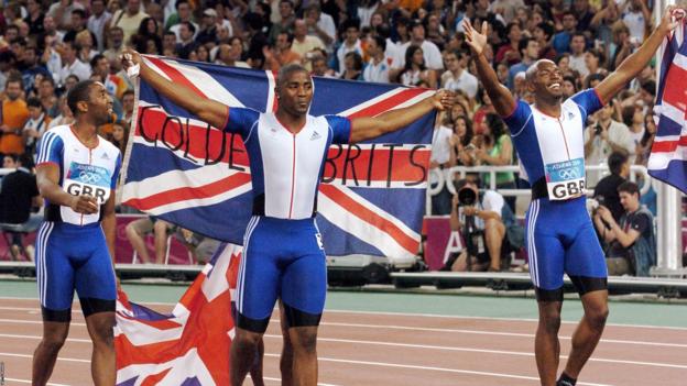 Britain's men's 4x100m team members Mark Lewis-Francis (C), Darren Campbell (L), and Marlon Devonish celebrate their gold in August 2004 at the Athens Olympics