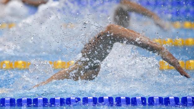 Unidentified swimmers' arms in a pool