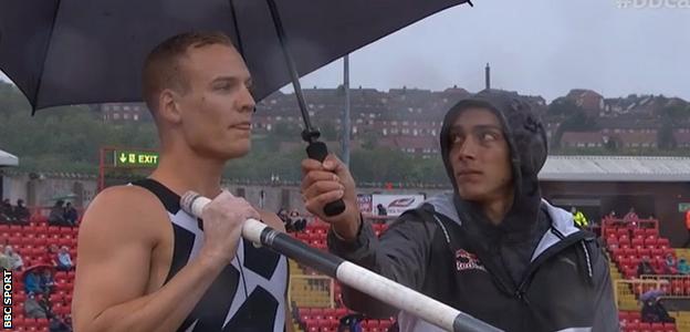 Mondo Duplantis holds an umbrella for Sam Kendricks