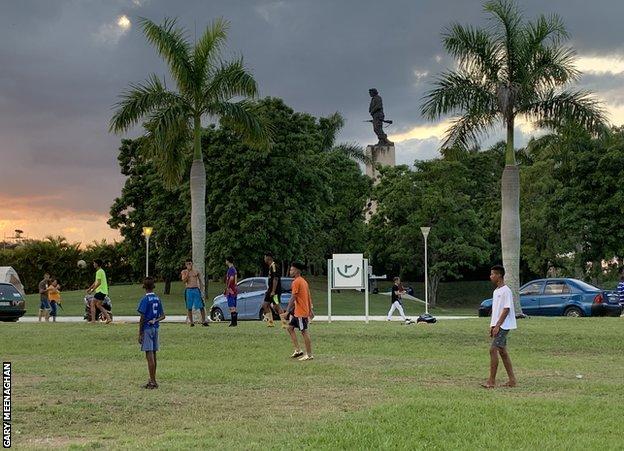 A group of youths play football at the feet of a statue of Che Guevara