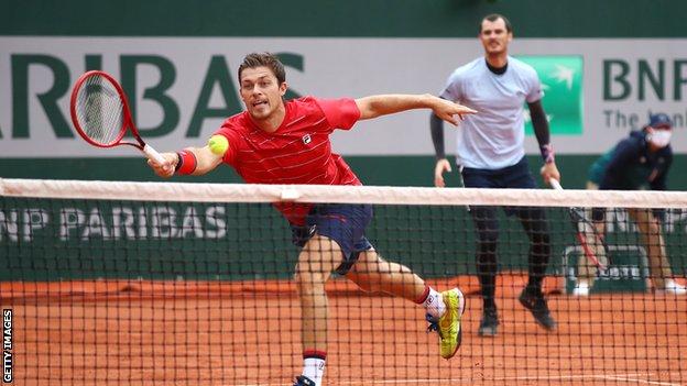 Neal Skupski reaches for the ball as Jamie Murray looks on