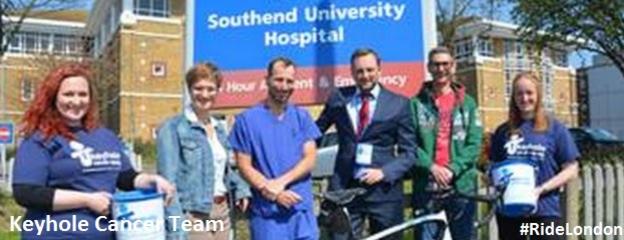 6 people in front of Southend University Hospital, 3 women and 3 men smiling one bike in front of the people