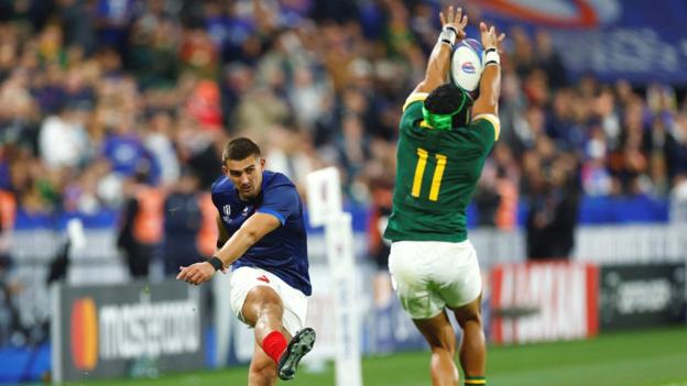 South Africa winger Cheslin Kolbe is seen from behind reaching up and charging down France full-back Thomas Ramos' conversion in their Rugby World Cup quarter-final