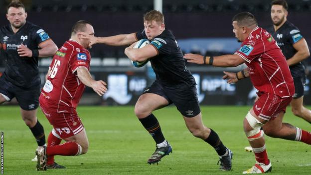 Ospreys flanker Jac Morgan hands off Scarlets hooker Ken Owens