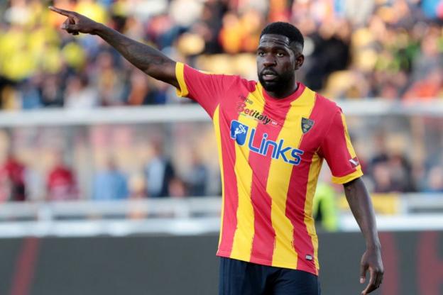 Samuel Umtiti raises his arm in the air to his right and points his finger]