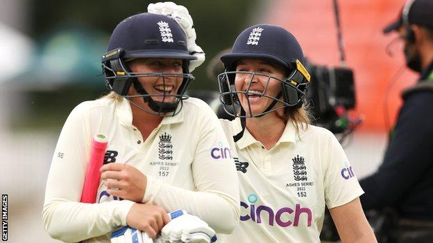 England batters Sophie Ecclestone (left) and Kate Cross (right) laugh as they walk off after drawing a dramatic Ashes Test against Australia