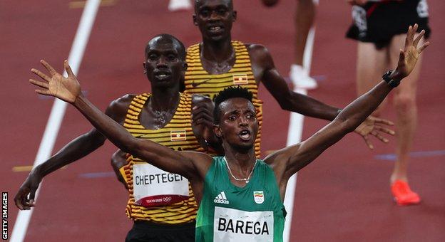 Ethiopia's Selemon Barega crosses the finish line ahead of second-placed Uganda's Joshua Cheptegei and Uganda's Jacob Kiplimo in the men's 10,000m final during the Tokyo 2020 Olympic Games