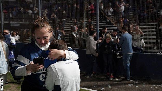 Fans break through the fence to enter the Carmelo Zerillo stadium in La Plata
