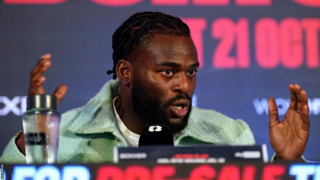 Joshua Buatsi speaks and holds out his hand during a news conference