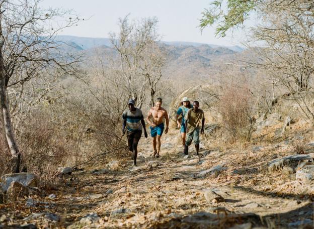 Two Hadza men accompany two visitors on a run through their territory