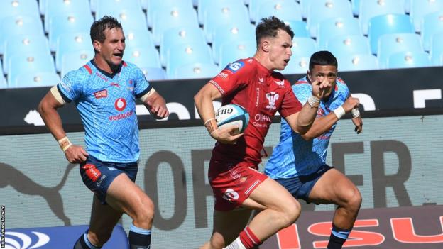 Tom Rogers runs past two players