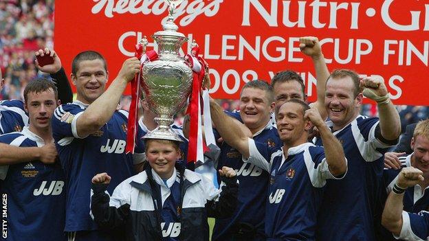 Andy Farrell places the trophy on Owen Farrell's head as the Wigan team celebrate