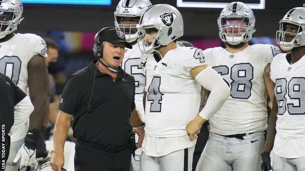 Jon Gruden speaks with Las Vegas Raiders quarterback Derek Carr