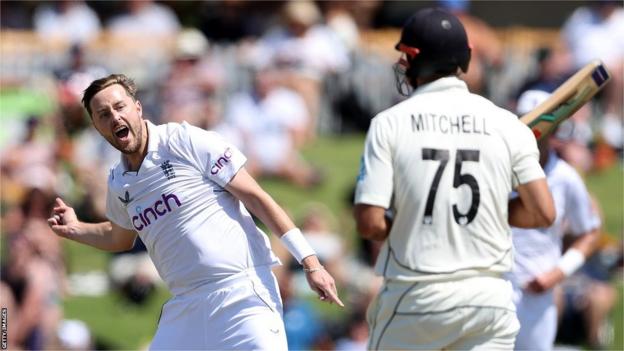 England bowler Ollie Robinson (left) celebrates dismissing New Zealand batter Daryl Mitchell (right)