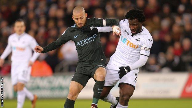 Wilfried Bony of Swansea City takes on David Silva of Manchester City