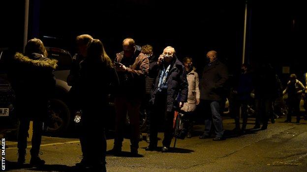 Fans form socially distanced queues as they wait to enter Adams Park