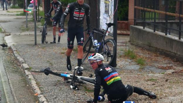 Remco Evenepoel on the pavement after he was involved in a crash caused by a dog wandering onto the road