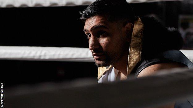 Amir Khan sits in corner of boxing ring.