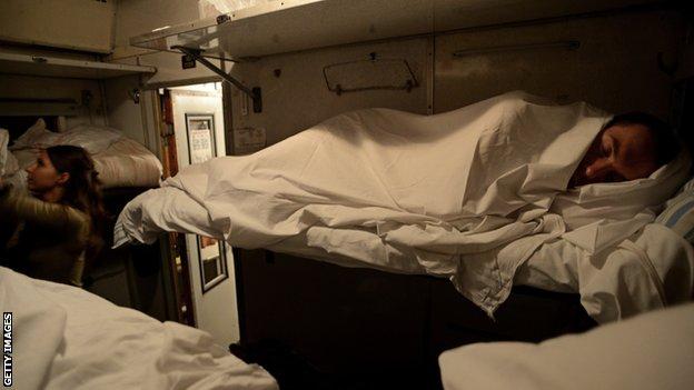 A man in a bed on a sleeper train in Russia