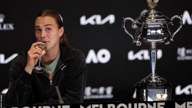 Aryna Sabalenka sips champagne during her news conference