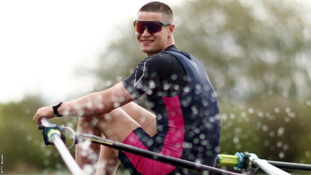 Callum Dixon rowing, smiling as he looks directly at the camera