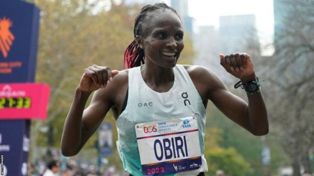 Hellen Obiri celebrates at the finish line with both arms raised