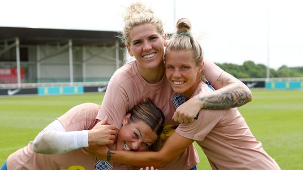 Millie Bright hugging Rachel Daly while also holding Mary Earps in a headlock