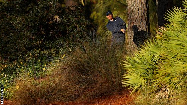 Rory McIlroy taking a shot out of the rough at the 10th