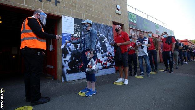 Fans queue socially distanced to enter a League One match between Charlton and Doncaster