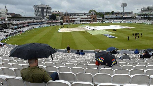 Spectators shelter from the rain at Lord's