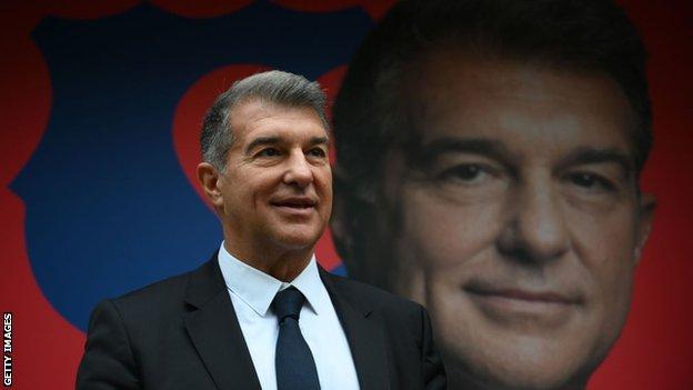 Joan Laporta stands in front of a billboard with his image on it