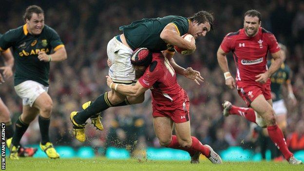 Eben Etzebeth of South Africa is taken down by Leigh Halfpenny of Wales